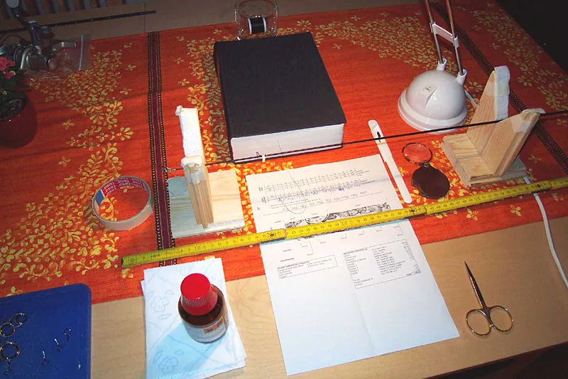 Ready to install the guides. - Setup with all necessary ingredients: Whiskey glass keeps the thread spool, book for thread tension, rod/blank holders for a stabel and steady turning and necessary tools like measuring tape, magnifying glass, scalpel, scissors, masking tape and some cleaning alcohol.